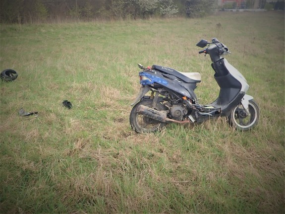 Na zdjęciu skuter zaparkowany na trawie.
