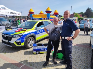 Na zdjęciu policjant umundurowany oraz mężczyzna podczas motoryzacyjnego wydarzenia w Będzinie.