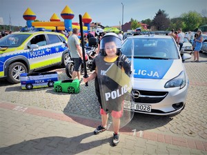 Na zdjęciu chłopczyk przebrany za policjanta stoi z tarczą i pałką.