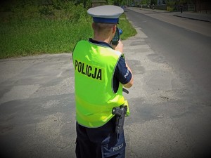 Policjant stojący przy drodze z radarem.