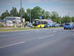 Na zdjęciu widzimy ludzi przechodzących przez przejście dla pieszych. Obok przejścia znajduje się umundurowany policjant.