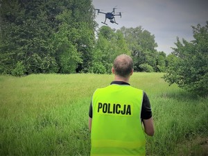 Zdjęcie przedstawia policjanta, który steruję dronem.