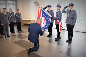 Zdjęcie, na którym widzimy klękającego przed sztandarem Komendy Powiatowej Policji w Będzinie nowego komendanta.