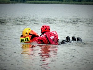 Na zdjęciu strażak wyławia innego strażaka podczas ćwiczeń na zalewie.