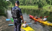 dwaj kajakarze w kajakach, na pomoście policjant