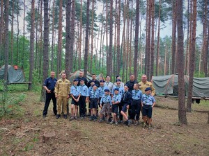 Na zdjęciu policjant, strażacy i harcerze w lesie .