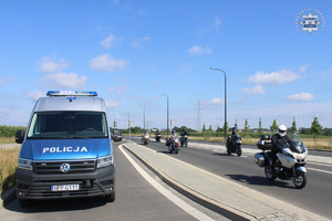 Na zdjęciu radiowóz policyjny, a obok jadący po drodze motocykliści.