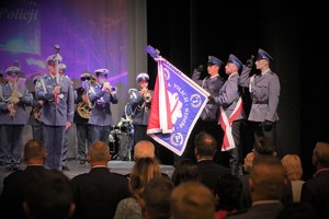 Na zdjęciu policjanci sztandaru Komendy Powiatowej Policji w Będzinie oraz policyjna orkiestra na scenie.