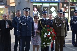 Na zdjęciu przedstawiciele służb mundurowych,którzy składają kwiaty pod tablicą pamiątkową.