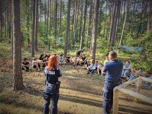 Na zdjęciu policjanci prowadzą prelekcje w lesie dla grupy harcerskiej.