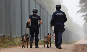 Na zdjęciu dwóch policjantów podczas patrolu z psami policyjnymi.