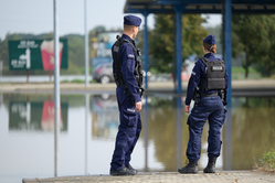 Na zdjęciu policjantka i policjant przed wylaną wodą.