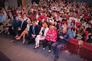 Na zdjęciu widzimy grupę osób zasiadających w teatrze podczas spektaklu. W pierwszym rzędzie widoczni zaproszeni goście.