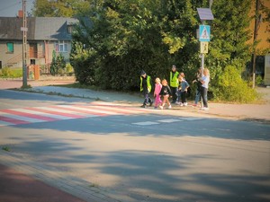 Na zdjęciu policjantki przechodzą z dziećmi przez oznakowane przejście dla pieszych.