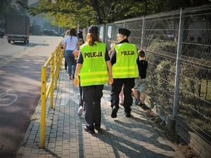 Na zdjęciu dwie policjantki idą za grupą dzieci do szkoły.