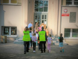 Na zdjęciu grupa dzieci z policjantkami wchodzi do szkoły.