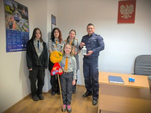 Zdjęcie grupowe harcerek i Zastępcy Komendanta Powiatowego Policji w Będzinie w jego gabinecie.