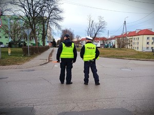 Na zdjęciu umundurowani policjanci stoją z alkomatami na drodze.