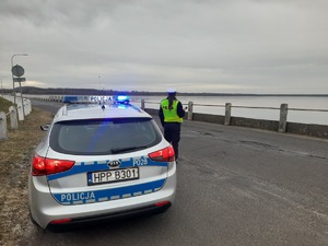 Na zdjęciu policjantka stojąca z alkomatem przy radiowozie.