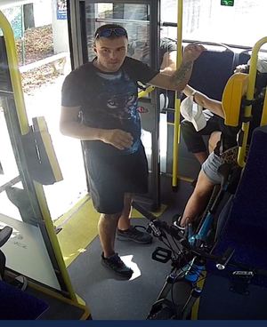 Na zdjęciu mężczyzna w autobusie stoi przy niebieskim rowerze.