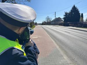 Na zdjęciu policjant z miernikiem prędkości przy ulicy.