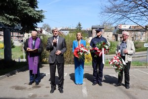 Na zdjęciu widzimy księdza oraz delegacje do złożenia kwiatów pod obeliskiem.