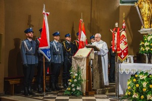 Na zdjęciu ksiądz prowadzący Mszę Świętą w kościele, za nim stoi poczet sztandarowy z Komendy Powiatowej Policji w Będzinie.