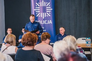 Na zdjęciu policjant wita zgromadzonych uczestników debaty z seniorami.