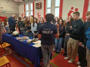Na zdjęciu grupa młodzieży przed promocyjnym stanowiskiem Policji podczas otwartych dni w siewierskiej szkole.