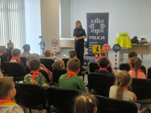 Na zdjęciu policjantka prowadzi prelekcje dla grupy dzieci.