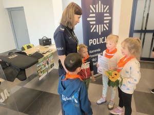 Na zdjęciu przedszkolaki wręczają policjantce podziękowanie i kwiaty.