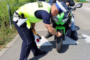 Na zdjęciu policjant sprawdza stan bieżnika w skuterze.