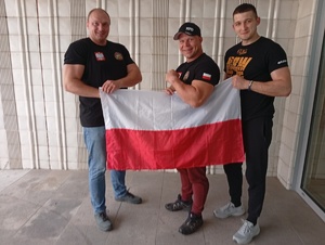 Na zdjęciu trzech mężczyzn trzymających biało-czerwoną flagę.