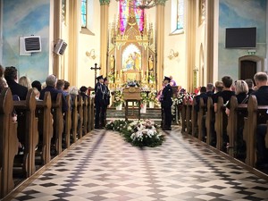 Na zdjęciu policjanci stoją przy trumnie w kościele.