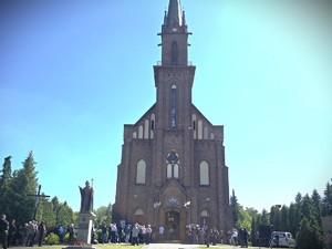 Zdjęcie przedstawia kościół oraz ludzi stojących przed nim.