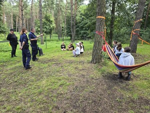 Na zdjęciu widzimy policjantkę i policjanta, którzy rozmawiają z uczestniczkami półkolonii jeździeckich.