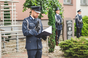 Na zdjęciu policjant przemawiający do ludzi.