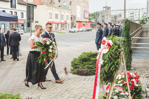 Na zdjęciu kobieta reprezentująca Prezydenta Będzina z mężczyzną składają kwiaty pod obeliskiem.