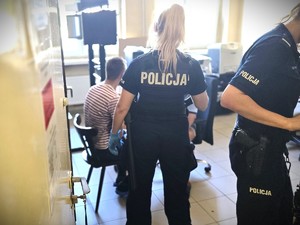Na zdjęciu policjantka i siedzący na krześle zatrzymany.