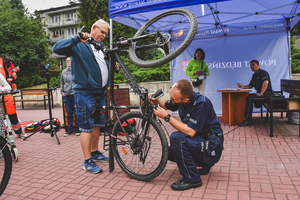 Na zdjęciu policjant znakuje rower mężczyźnie.