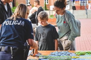 Na zdjęciu policjantka przy stanowisku profilaktycznym z dwójką dzieci.