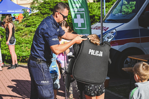 Na zdjęciu policjant zakłada chłopcu strój policjanta na mecze piłkarskie.