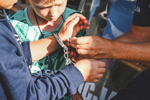 Na zdjęciu policjant pokazuje dzieciom kajdanki.