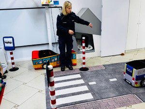 Na zdjęciu policjantka prezentuje mobilne miasteczko drogowe przedszkolakom.