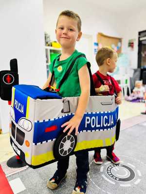 Na zdjęciu dwóch chłopców w autochodziku imitującym policyjny radiowóz.