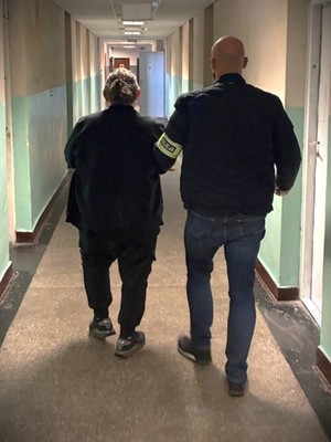 Na zdjęciu policjant pionu kryminalnego doprowadza zatrzymanego mężczyznę.