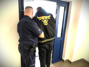 Na zdjęciu policjant wyprowadza zatrzymanego z policyjnego aresztu.
