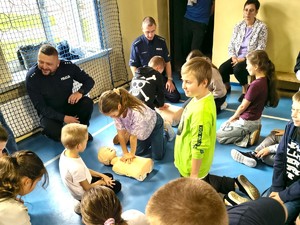 Zdjęcie grupowe dzieci i policjantów na sali gimnastycznej.