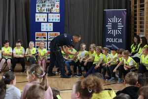 Na zdjęciu policjant rozdaje uczniom odblaski.