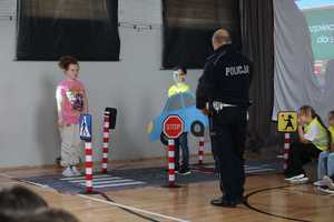 Na zdjęciu policjant uczy przepisów z wykorzystaniem mobilnego miasteczka ruchu drogowego.